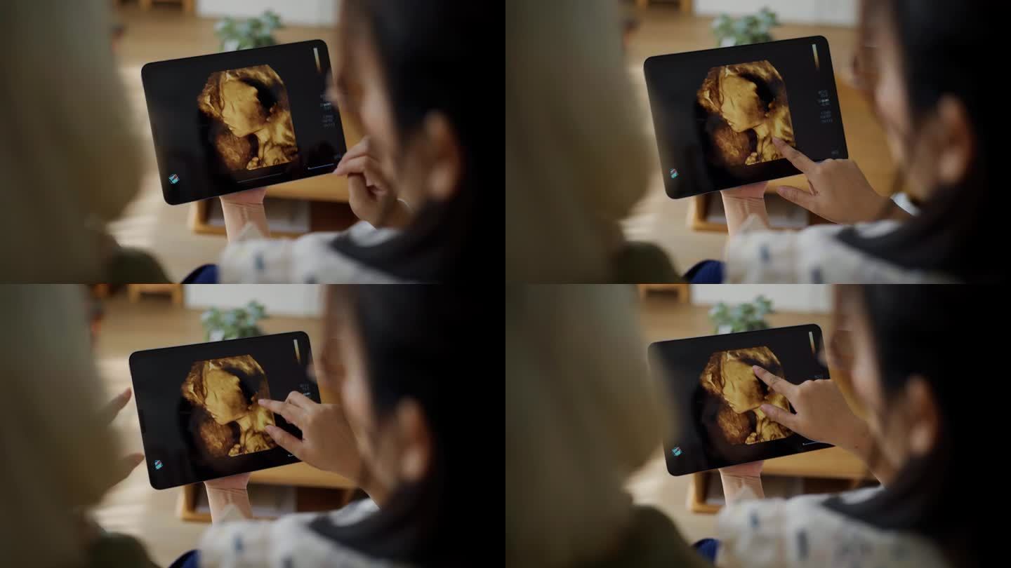 幸福的亚洲家庭在客厅里看着平板电脑上婴儿的超声波图像交谈的后视图
