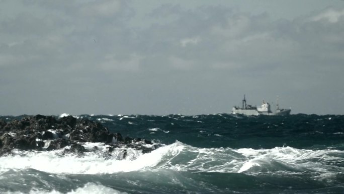岩石海岸附近的风暴和海上的渔船(慢动作)