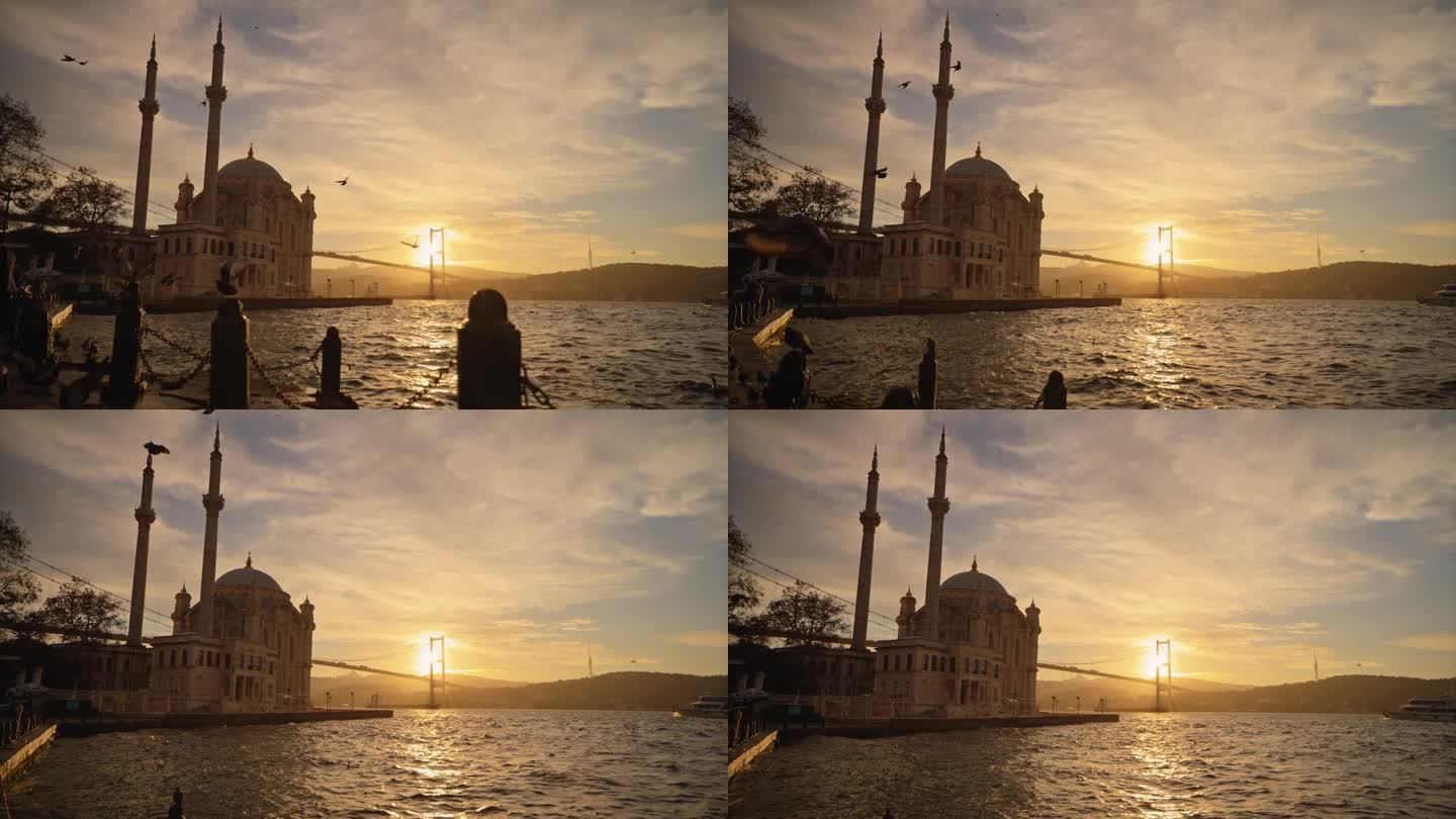 奥尔塔科伊宏伟清真寺的黄昏宁静:鸽子的剪影从伊斯坦布尔的海滨长廊上翱翔到奥尔塔科伊宏伟的清真寺和桥梁