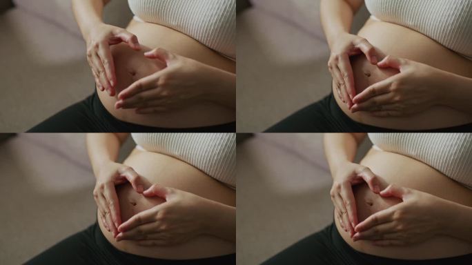 怀孕的女人在她的肚子上做一个心形的手势