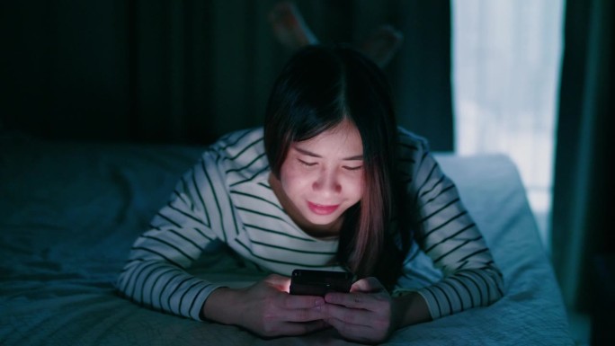 晚上躺在床上玩手机的女人