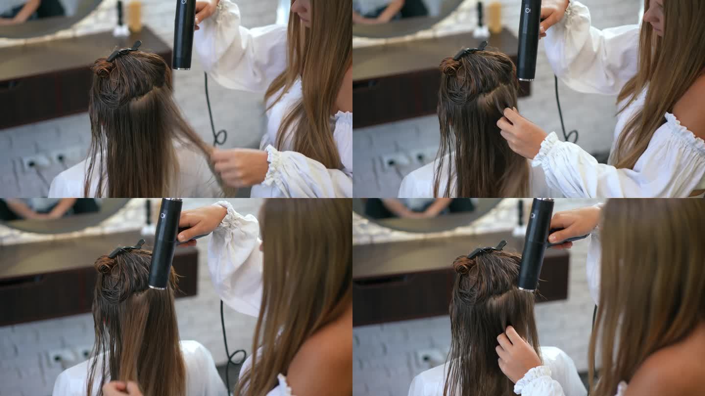 缓慢的运动。在美发沙龙里，一位女理发师正在用吹风机给坐在椅子上的顾客吹湿头发。