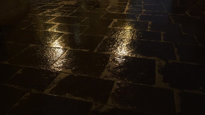 特写:街灯的光线反射在潮湿的城市地面上