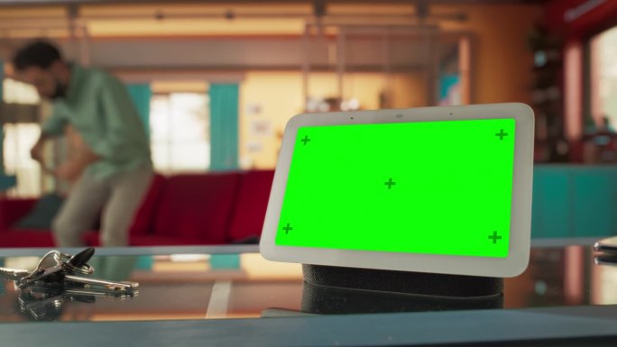 创意智能家居设备与绿色屏幕显示。在后台的人使用智能手机来控制他的时尚家居环境。物联网高科技无线智能系