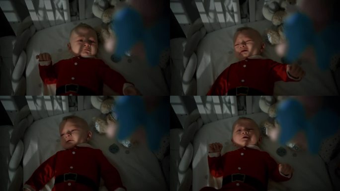 正上方，穿着圣诞老人服装的不舒服的男婴躺在家里的婴儿床上哭泣