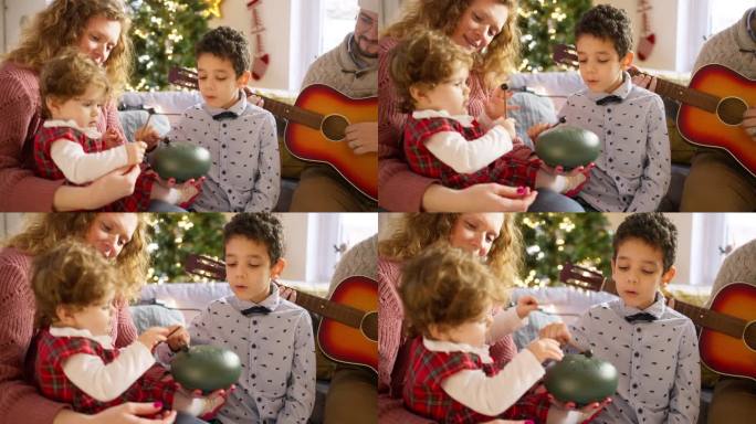 白种人父母带着孩子一边玩原声吉他和舌鼓一边庆祝圣诞节
