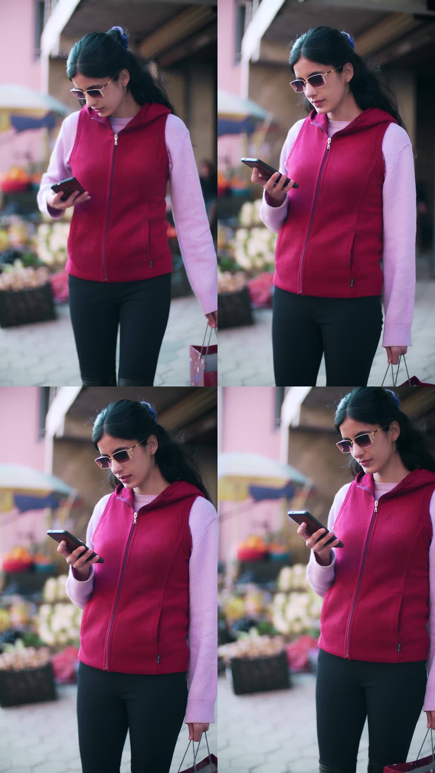 一名女子在一家蔬菜水果店购物后查看她的智能手机。