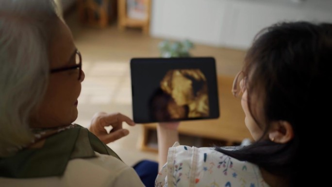 兴奋的亚洲家庭在平板电脑上观看婴儿的超声波图像
