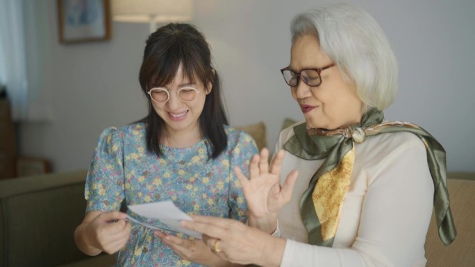 一名孕妇和她的母亲在舒适的客厅里看着未出生婴儿的超声波扫描，一起聊天。