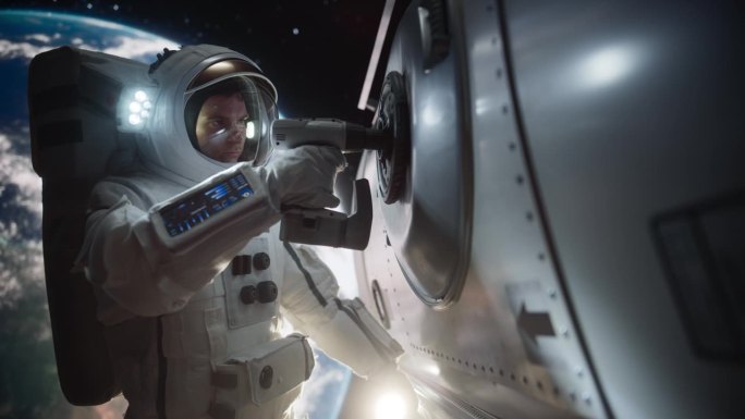 太空工程师正在用自动螺旋枪修理空间站的入口舱口。勇敢的宇航员在外太空工作，美丽的蓝色星球地球为背景