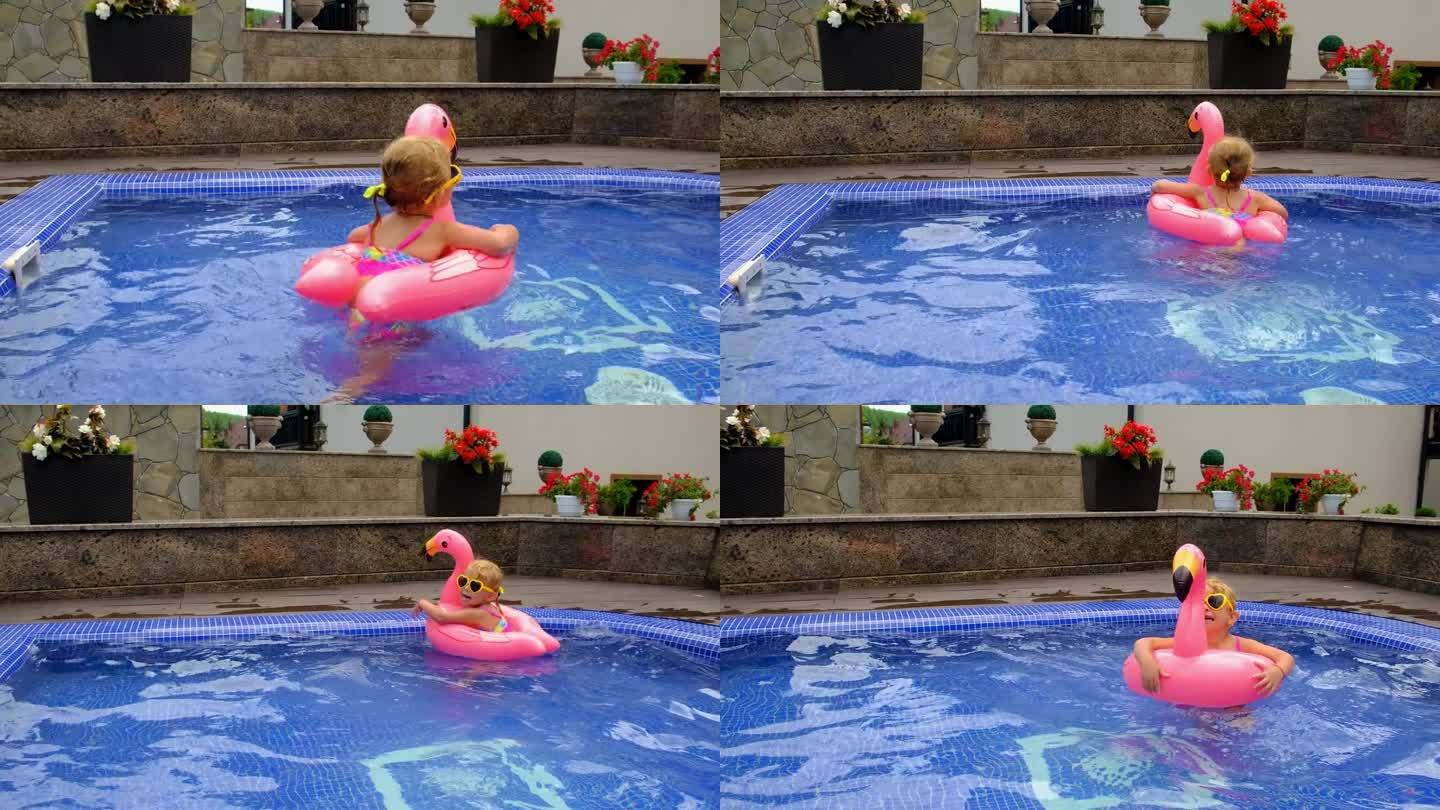 一个孩子在泳池里的火烈鸟圈里游泳。有选择性的重点。孩子。