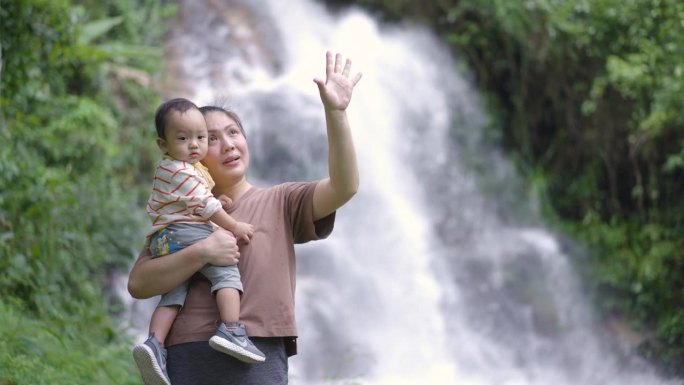 母亲带着儿子到瀑布外与大自然学习