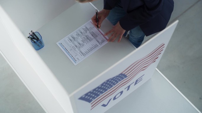 美国全国大选当天，一名女性在投票站填写纸质选票的画面。匿名妇女为当选官员投票