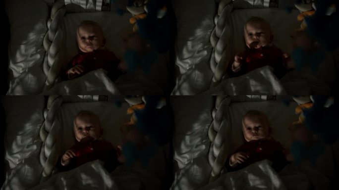 正上方的手持拍摄可爱的男婴躺在婴儿床在暗房白天