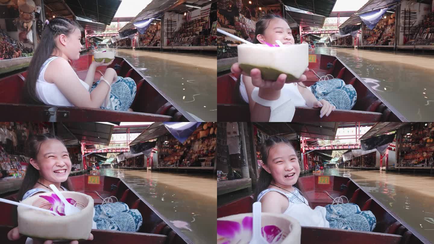 可爱的女孩在泰国水上市场的船上旅行时吃着椰子冰淇淋。