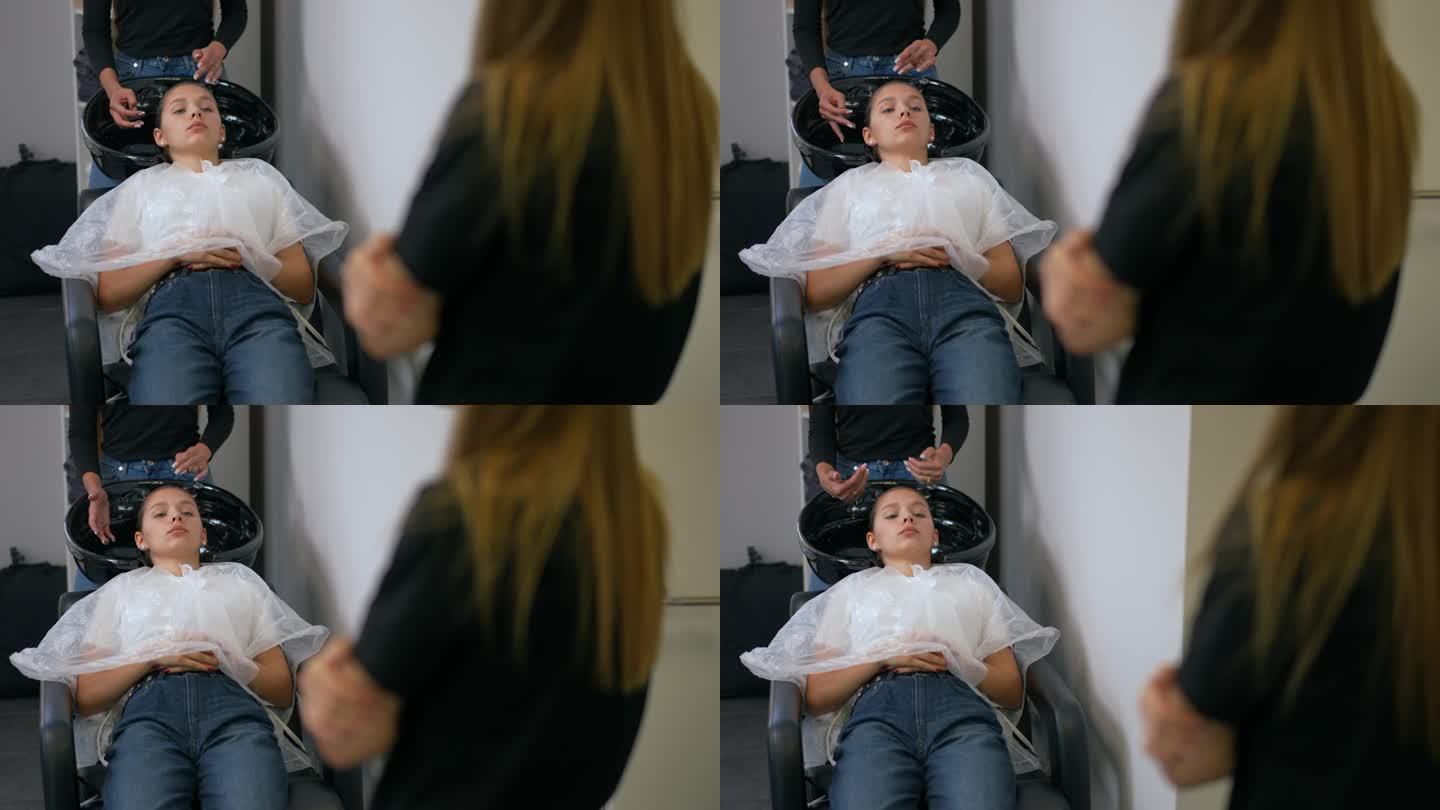 一位女理发师在谈论护发产品的好处，而一位女顾客躺在椅子上，头发上涂着香脂。