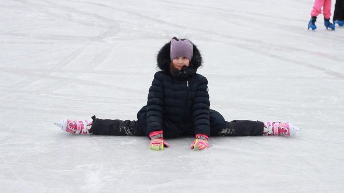 儿童冬季游戏和娱乐。一个十几岁的小女孩在溜冰场做劈叉。