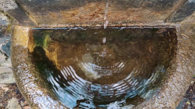 来自金属水龙头的泉水。特写镜头。前视图。在欧洲的森林里流淌着饮用水。