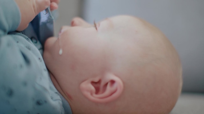在家沙发上宝宝脸颊上的牛奶滴的特写手持式镜头