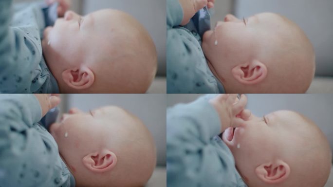 在家沙发上宝宝脸颊上的牛奶滴的特写手持式镜头