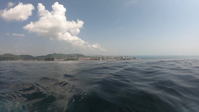 夏季室外游泳池的水波面，有城市景观和天空中的云