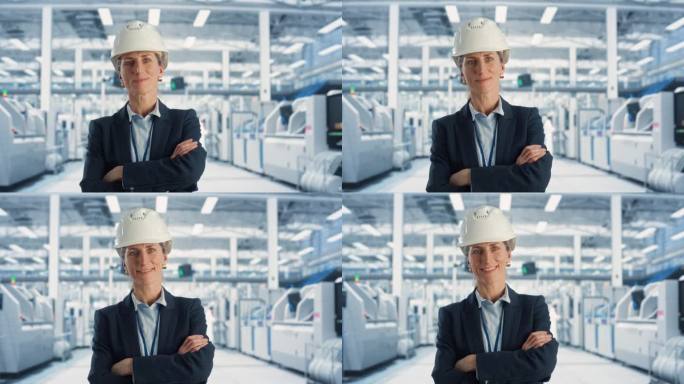 戴安全帽的白人女性设备技术员的肖像，双臂交叉站着，看着镜头，微笑着。工业专家在电子厂工作，生产高科技