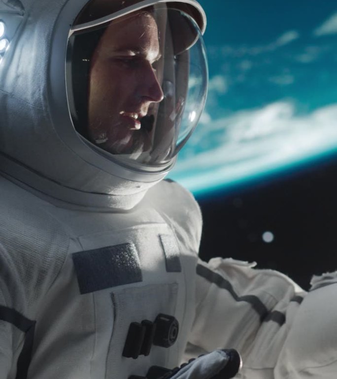 垂直屏幕:穿着太空服的兴奋男子在外太空与女友通话，旁边是一颗卫星。宇航员用智能手机与一位年轻女性进行