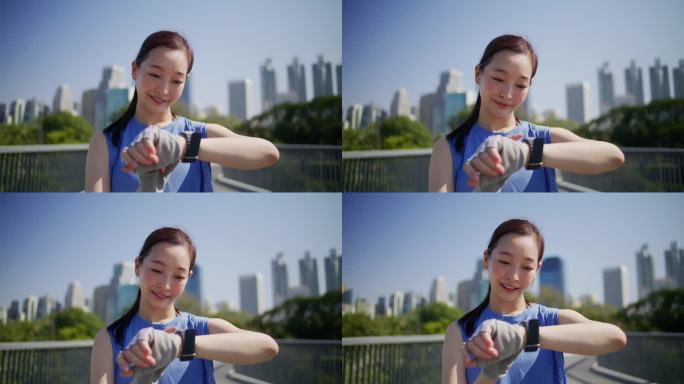 年轻的亚洲女子在城市公园路上慢跑后使用智能手表