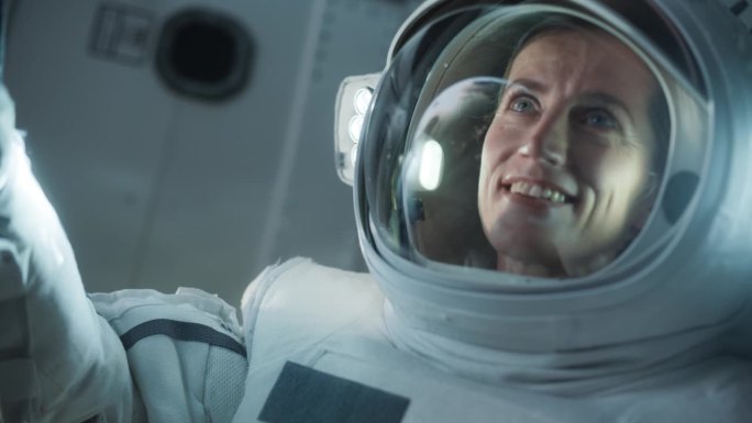 一位戴着头盔，穿着宇航服，从外太空看地球的激动快乐的女宇航员的肖像。科幻宇宙探险，发现和探索宇宙