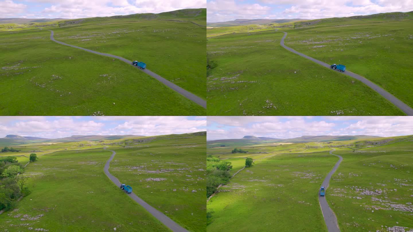 航拍:蓝色拖拉机满载着割过的草行驶在乡间小路上