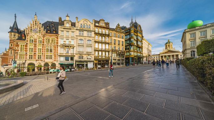 在比利时布鲁塞尔的城市街道上，一群游客在皇家广场和Wervelend Oor人行道上散步和观光