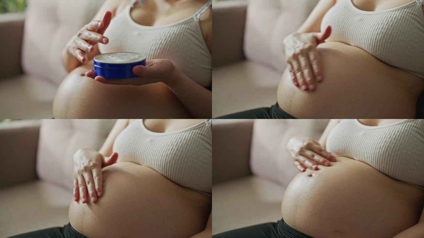 孕妇在家里给肚子涂润肤霜的特写