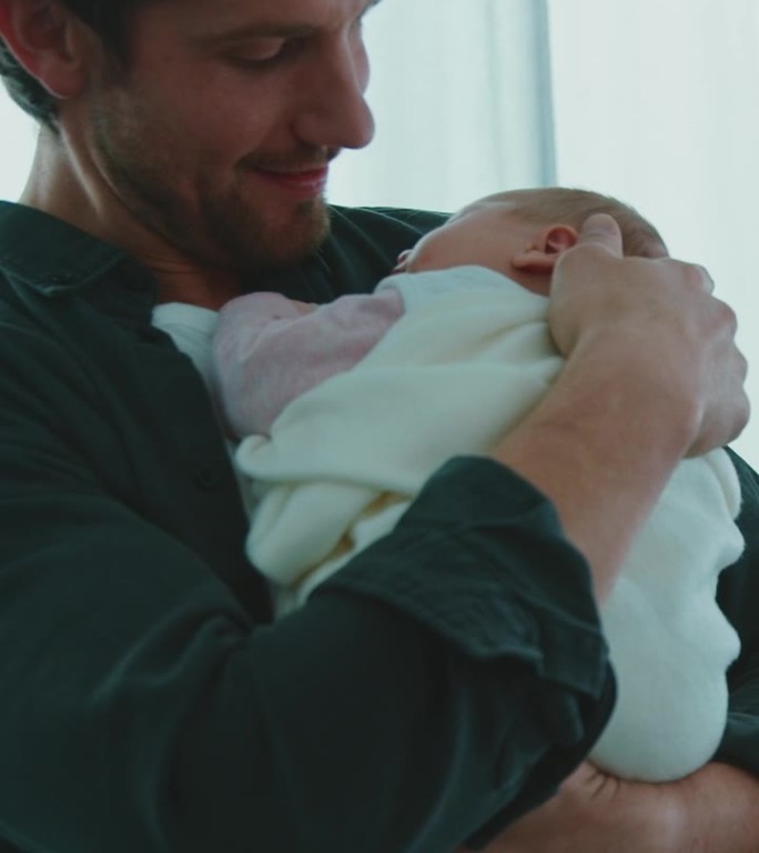 快乐的父亲在病房里抱着熟睡的新生儿