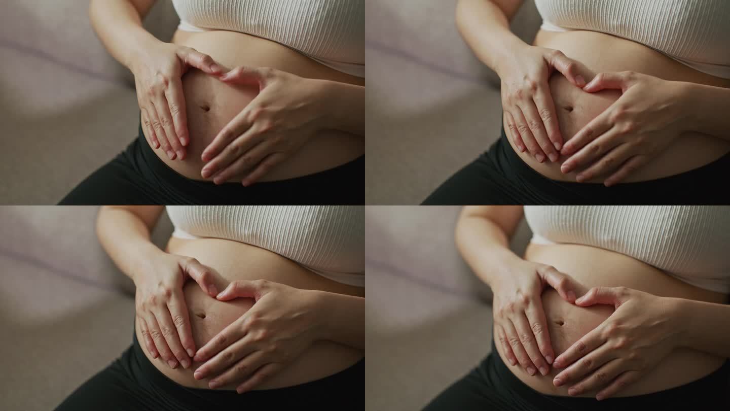 怀孕的女人在她的肚子上做一个心形的手势