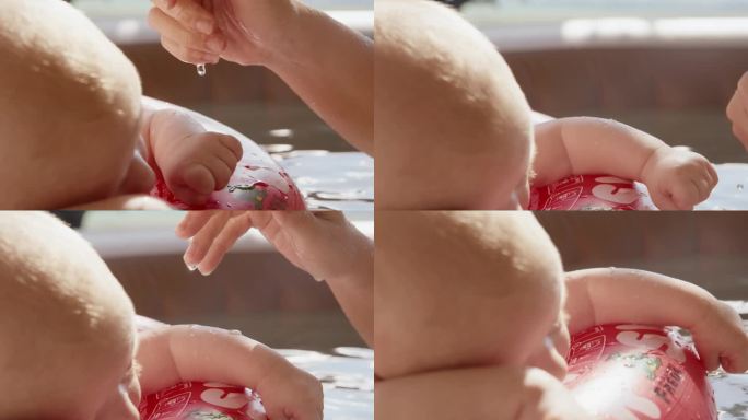 在家浴缸里漂浮的充气环上，妈妈的手在往小男孩身上滴水