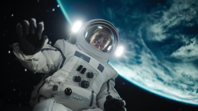 一个勇敢的女太空探险家的肖像漂浮在宇宙飞船外，表达幸福，微笑，积极的情绪。职业女性穿着太空服摆姿势，