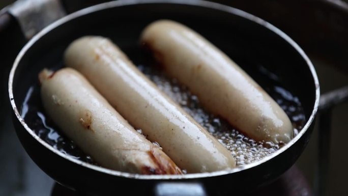 在煎锅里煎香肠。煎锅里的美味猪肉香肠