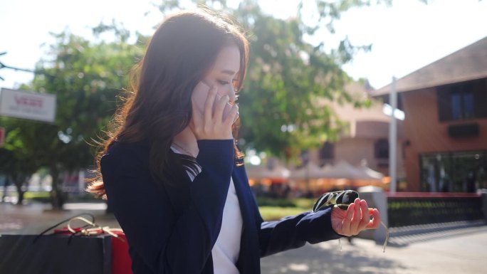 在一个阳光明媚的夏日，一个拎着购物袋的女人走在熙熙攘攘的城市街道上，周围的人，包括一个孩子和一对夫妇