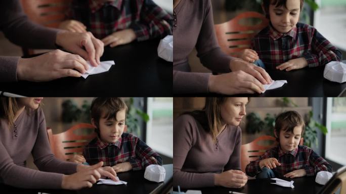 孩子男孩和母亲做折纸玩具使用彩色纸的步骤，按照指导的视频教程在数字平板电脑上
