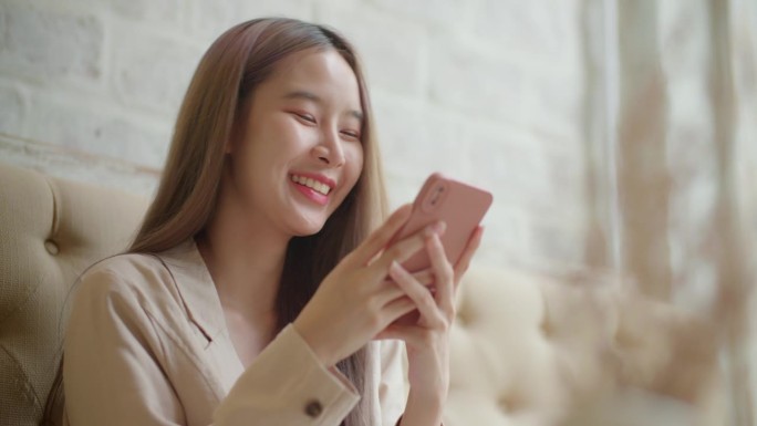 亚洲女性坐在智能手机上发短信、阅读和分享社交媒体。