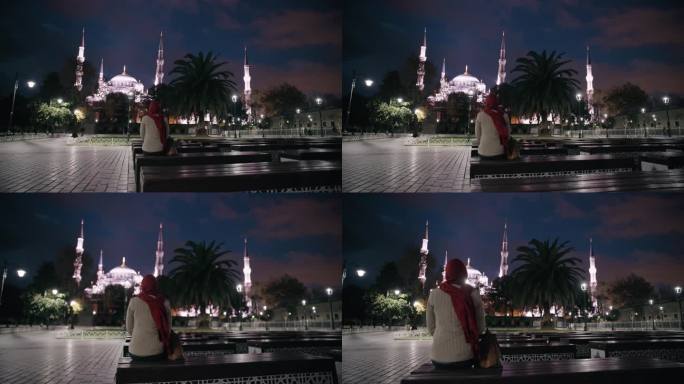 无法辨认的穆斯林妇女在灯火辉煌的广场上沉思圣索菲亚大教堂的雄伟之美#圣索菲亚之夜#宁静的反思#城市之