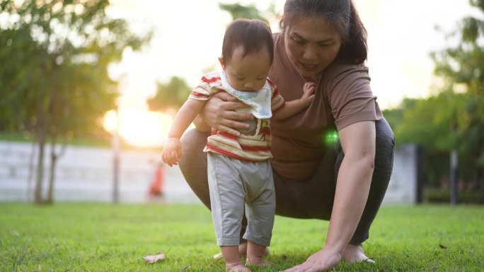 母亲在公园里训练她的儿子，让他学会迈出第一步