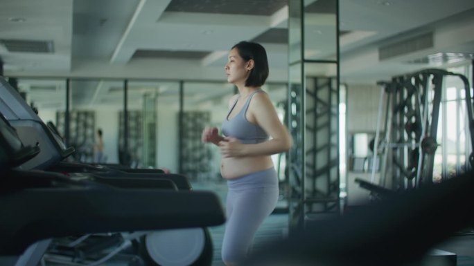 孕妇在健身房里在跑步机上锻炼