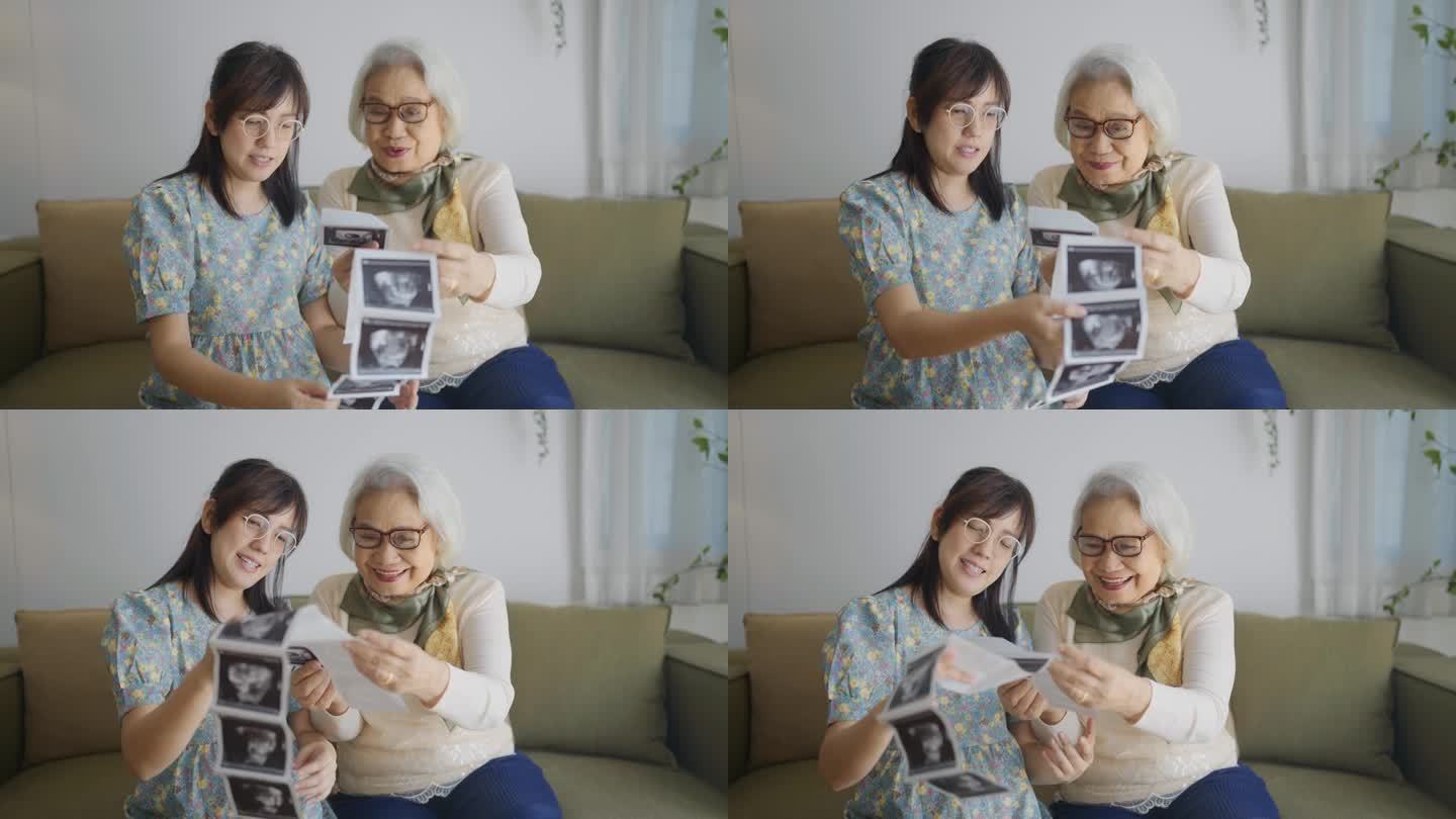 亚洲妇女和她的母亲度过美好的时刻在一起，他们分享爱的谈话，同时看着她的超声波扫描x射线婴儿出生在一起