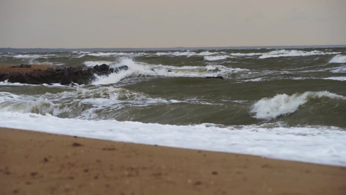 波涛汹涌的海浪冲击着沙滩上的岩石防波堤。自然的原始力量，暴风雨的大海镜头理想的天气预报，自然纪录片，