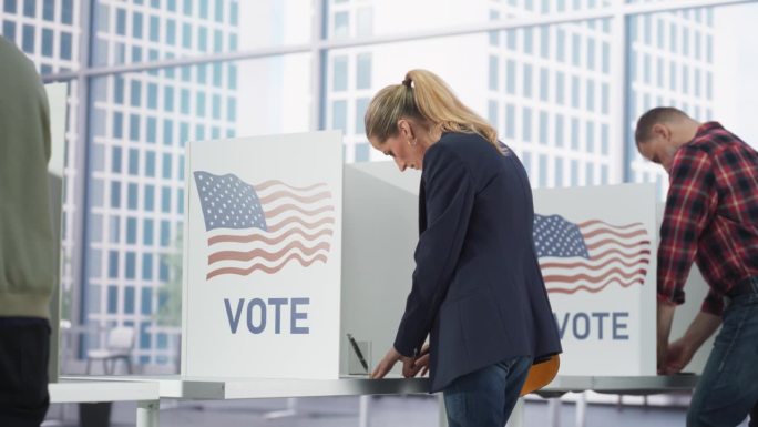 一位女商人在美国全国大选当天在投票站填写选票。在投票站为当选官员投票的成年男女。从背后看