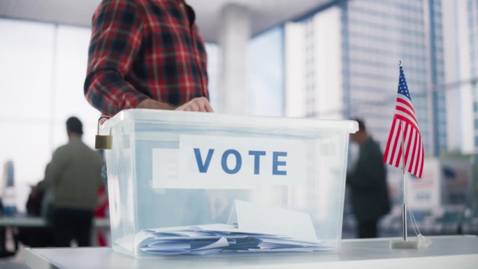 民主在行动:在一个现代投票站，成年白人男子把他的选票放进一个密封的盒子里。美国人民在美国选举日行使公