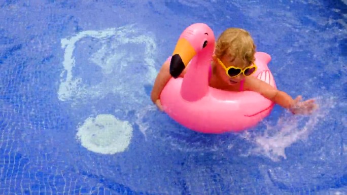 一个孩子在泳池里的火烈鸟圈里游泳。有选择性的重点。孩子。