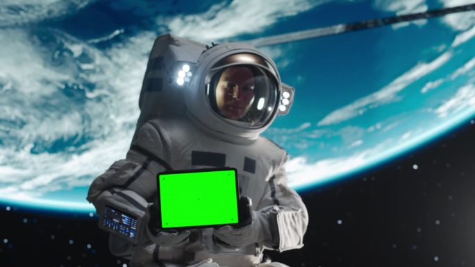 宇航员在外太空手持绿屏模拟显示的平板电脑。空间技术和探索模板概念的广告和营销活动