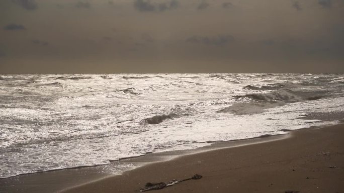 在暴风雨的天气里，大浪冲击着沙滩。乌云在头顶若隐若现，大海波涛汹涌。戏剧性的，自然的力量展示在海边。